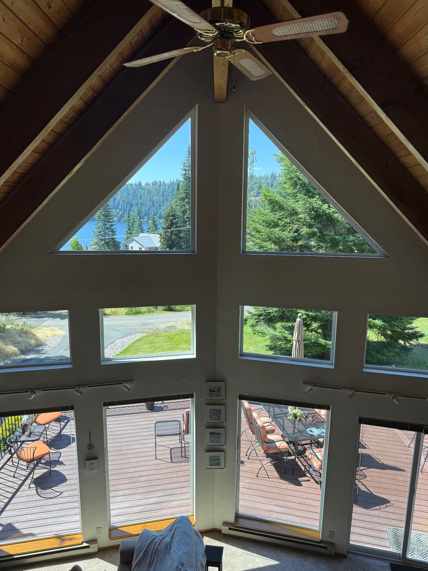 Interior view through spotless A-frame windows overlooking a lake and pines